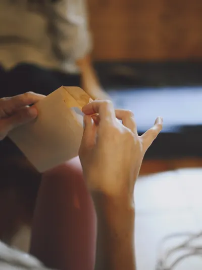 Manos abriendo un sobre de papel con el contenido oculto dentro